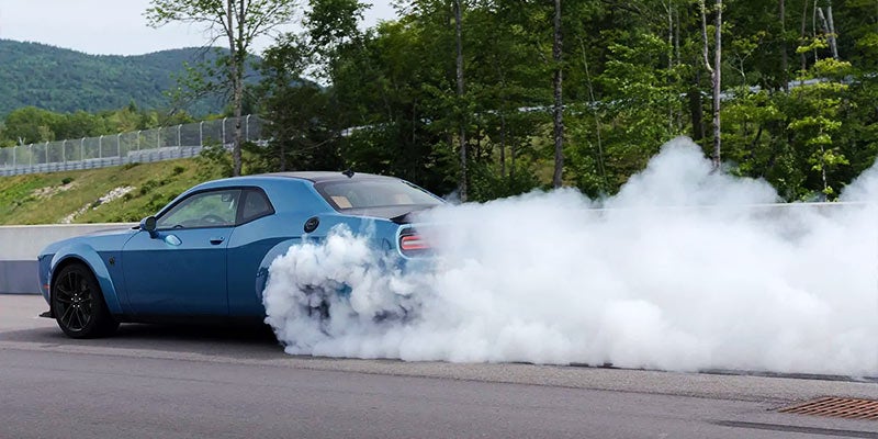 Blue Dodge Challenger burning out it's tires an creating a ton of smoke