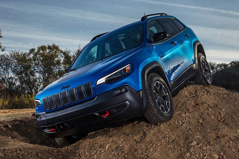 Jeep SUV driving down steep sandy slope