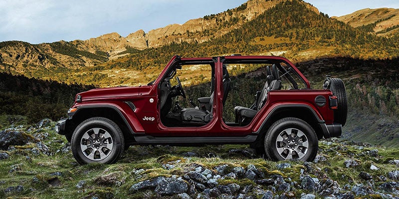 Maroon Jeep Wrangler parked on an open field while the sun is setting