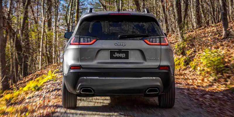 Gray Jeep Cherokee off roading into the forest while the sun is setting