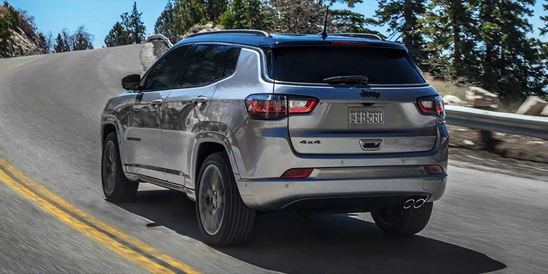 Gray Jeep Compass going up hill on the road during a sunny day