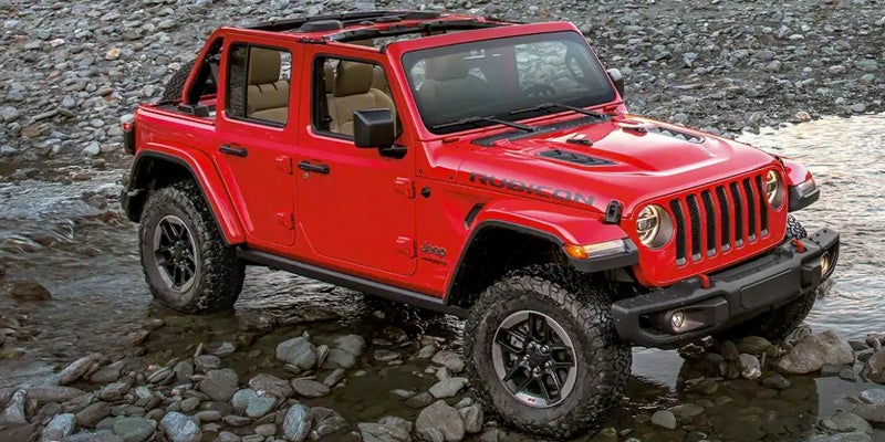 Red Jeep Wrangler parked by a small puddle and with rocks everywhere