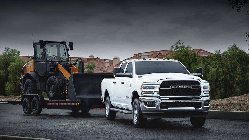 White Ram 2500 hitching a bulldozer from the construction site on a cloudy day