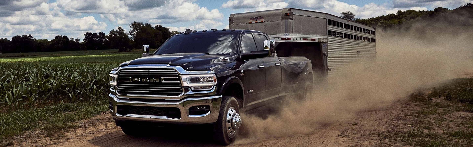 Black Ram 3500 driving down a dirt road kicking up dirt along the way