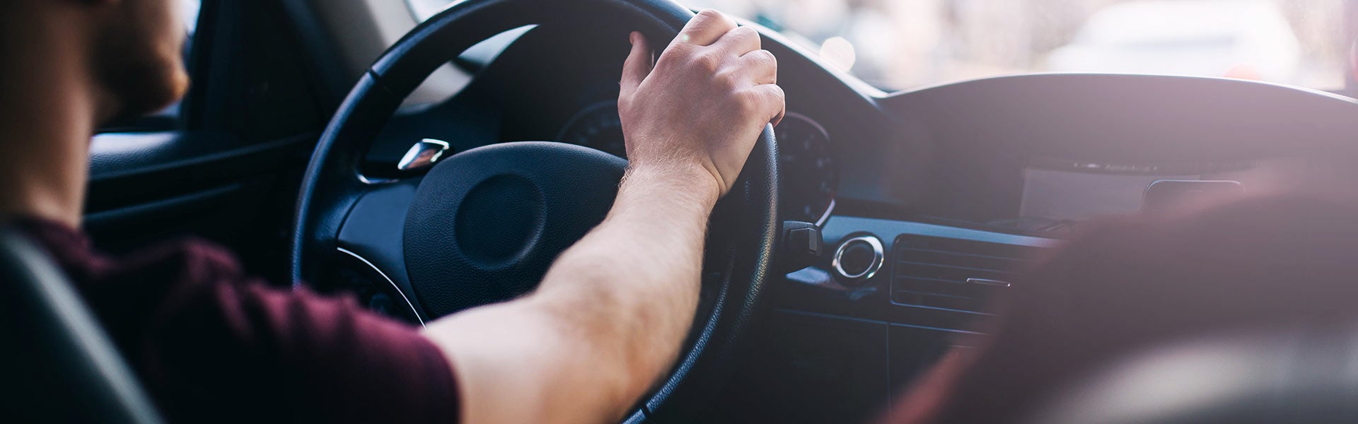 A man on driver seat with one hand on the steering wheel