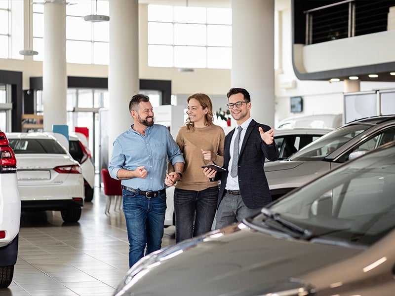 Couple holding hand while talking to car salesman