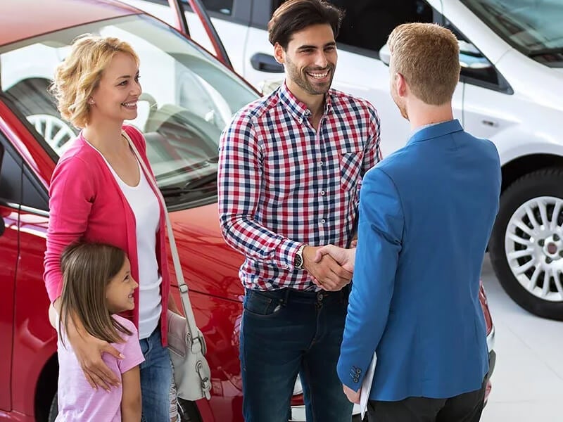 Family of car shopper greet with dealer sales person